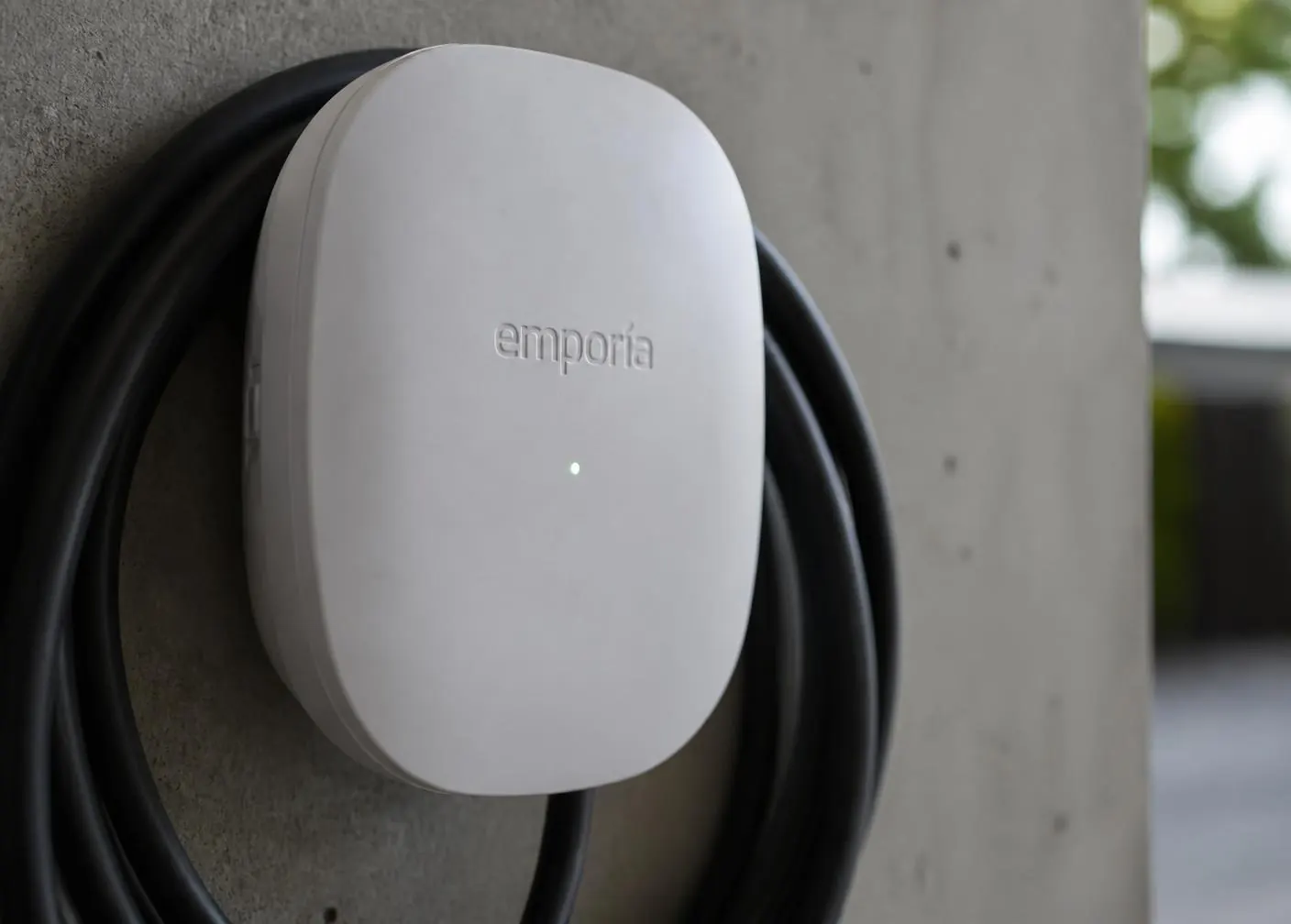 Close-up of a premium wall-mounted home EV charger with coiled cable